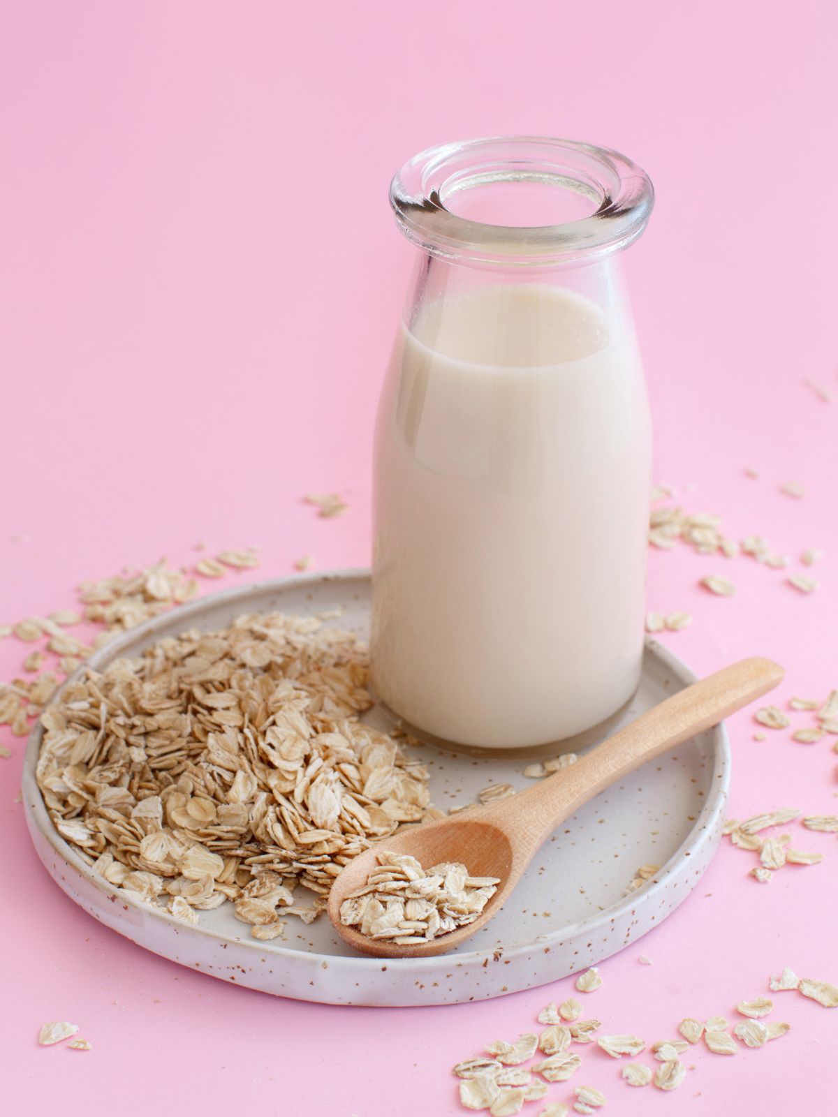 a jar of oat milk next to oats.