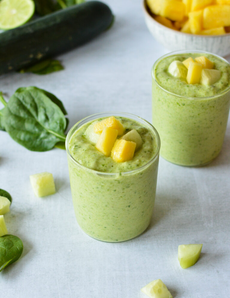 spinach cucumber smoothie with pineapple on top.