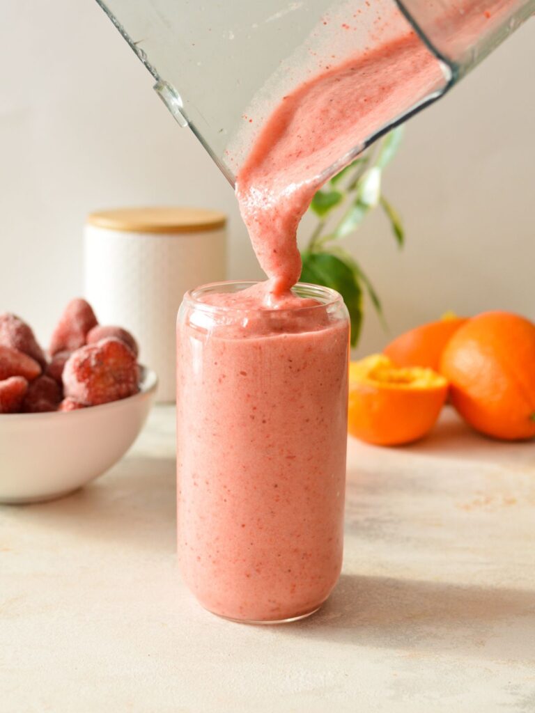 pouring a strawberry smoothie into a glass.