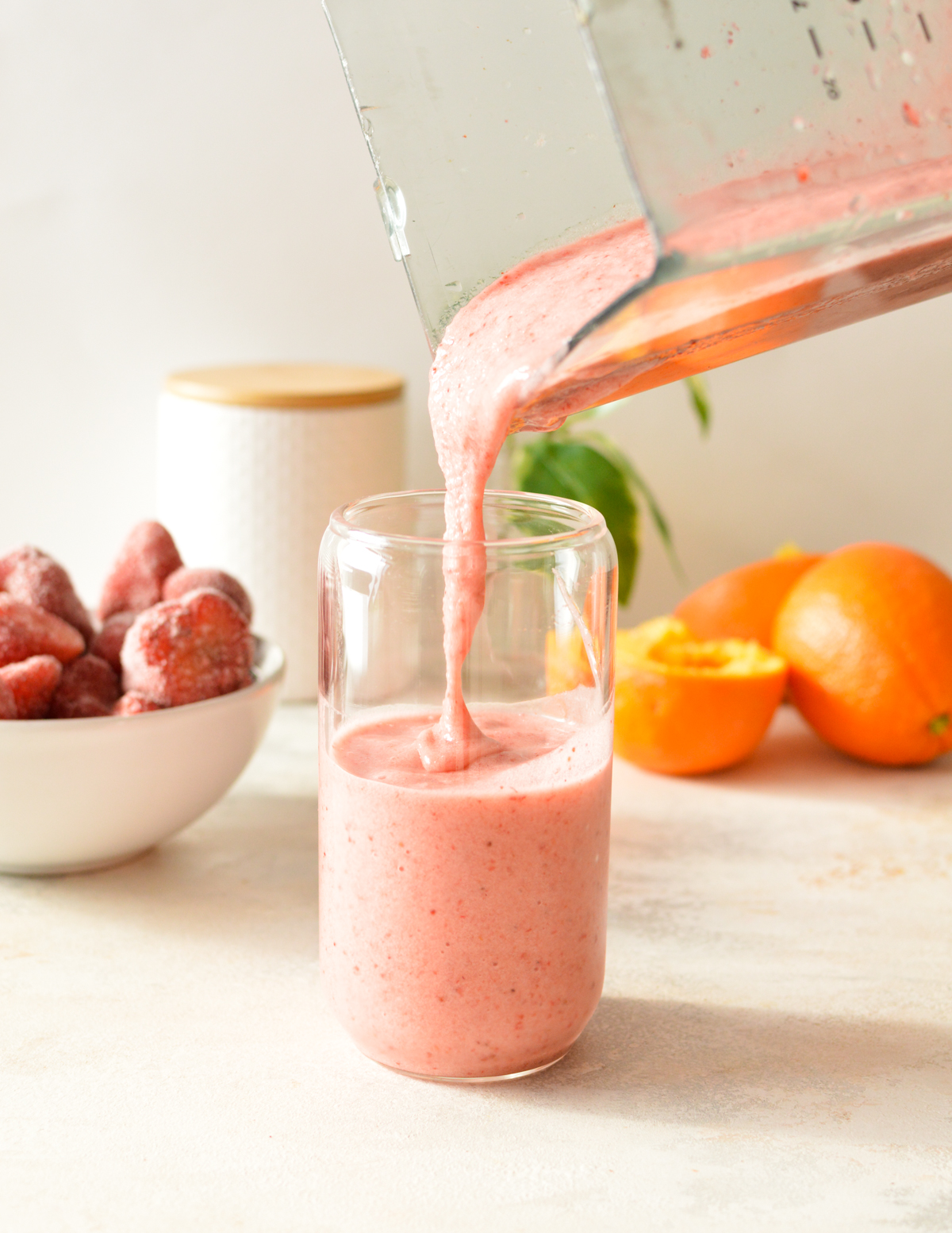 pouring strawberry smoothie into a glass.