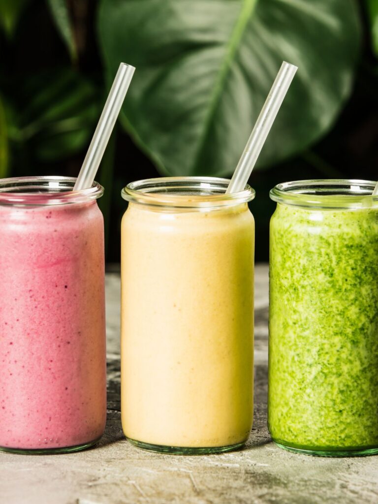 a berry smoothie, a green smoothie, and an orange smoothie.