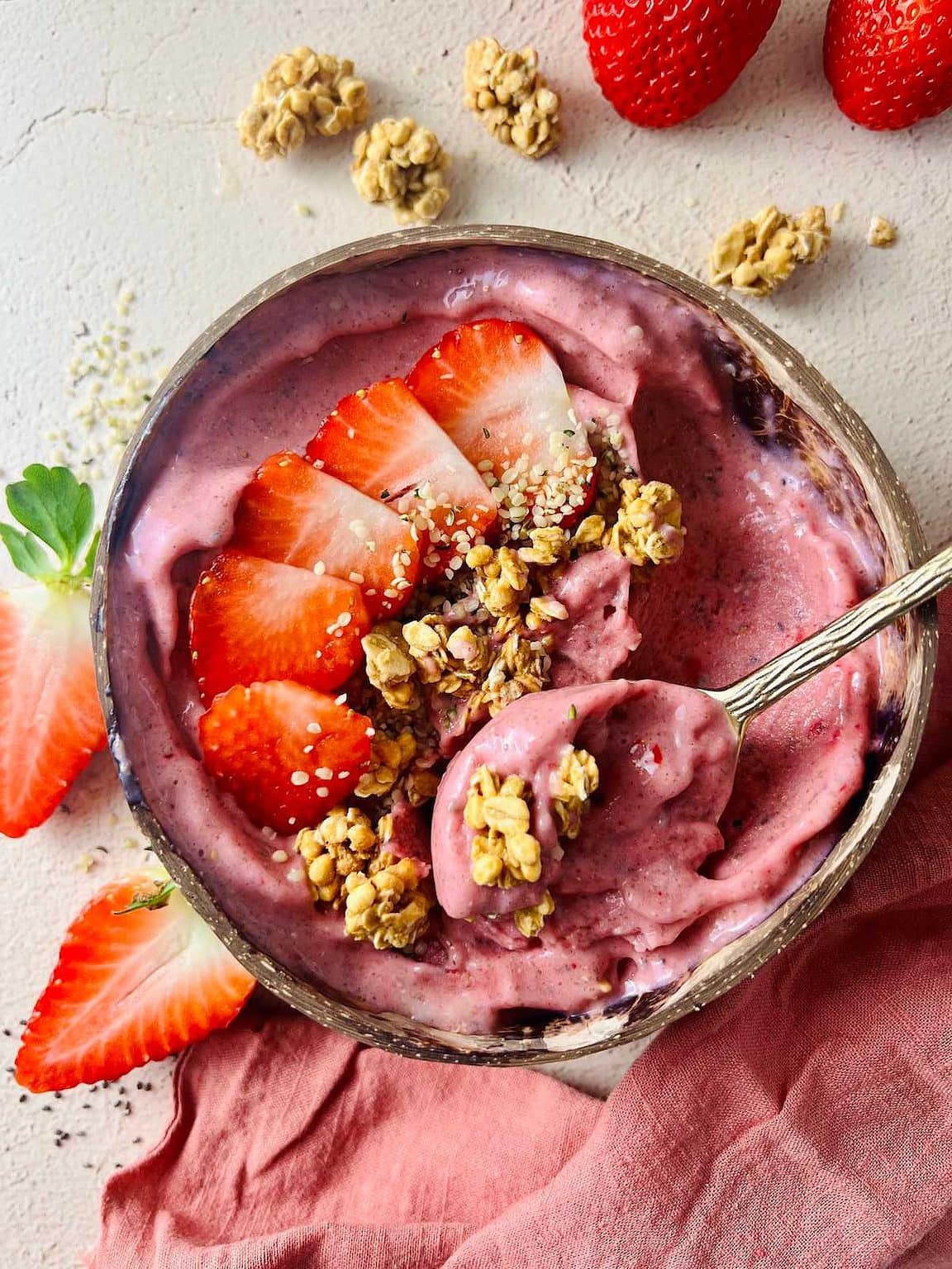 a strawberry smoothie bowl with fresh strawberries and granola.