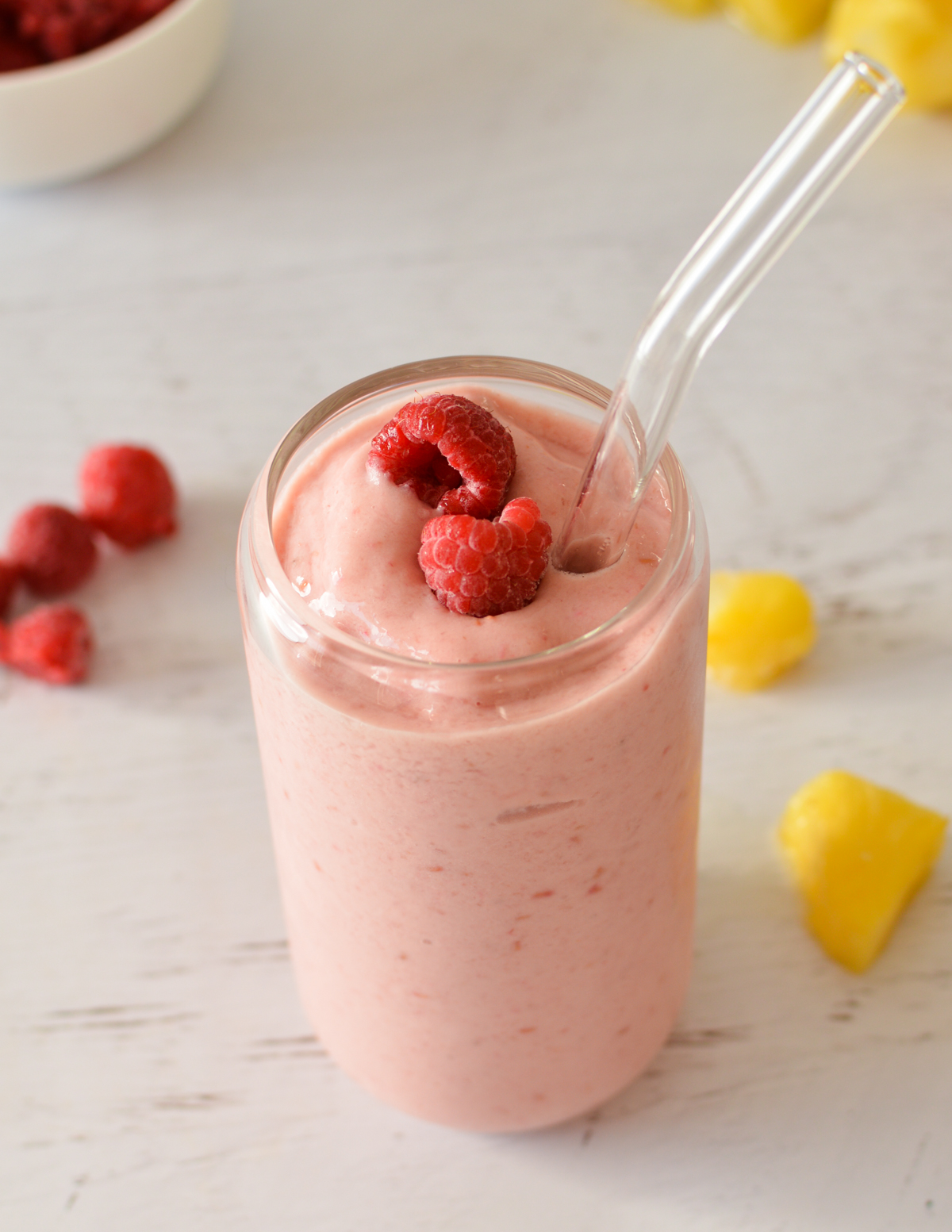 a pineapple raspberry smoothie with raspberries on top.