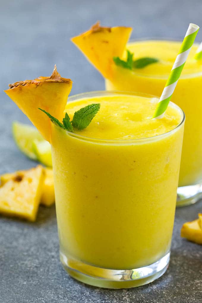 two pineapple smoothie with mint and a straw.