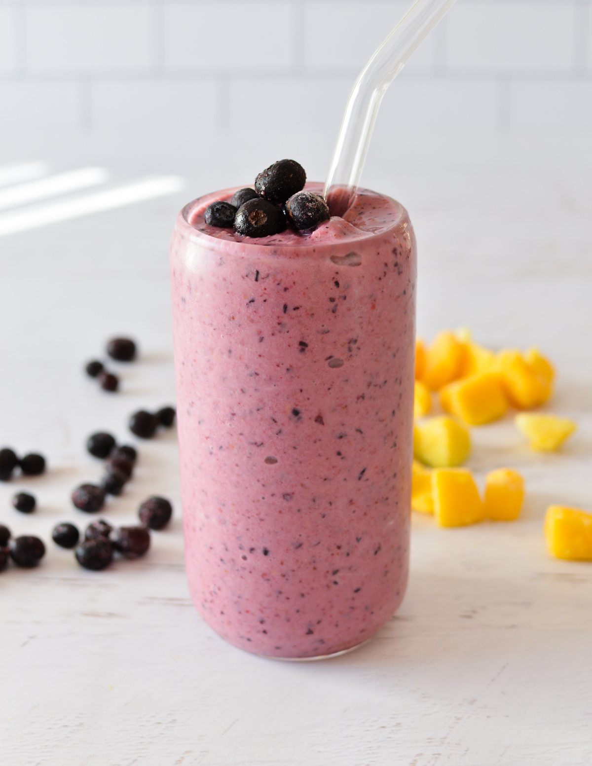 a mango berry smoothie with blueberries and mango next to it. 