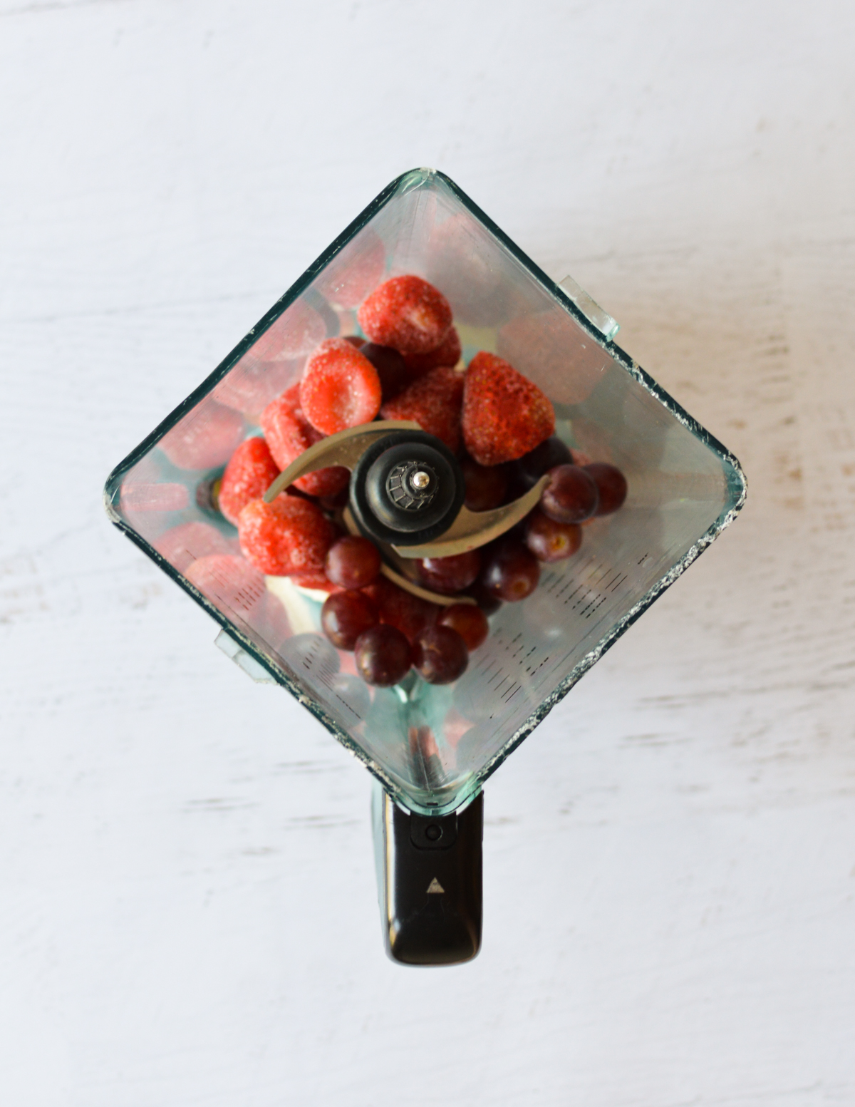 a blender with grapes and strawberries in it.