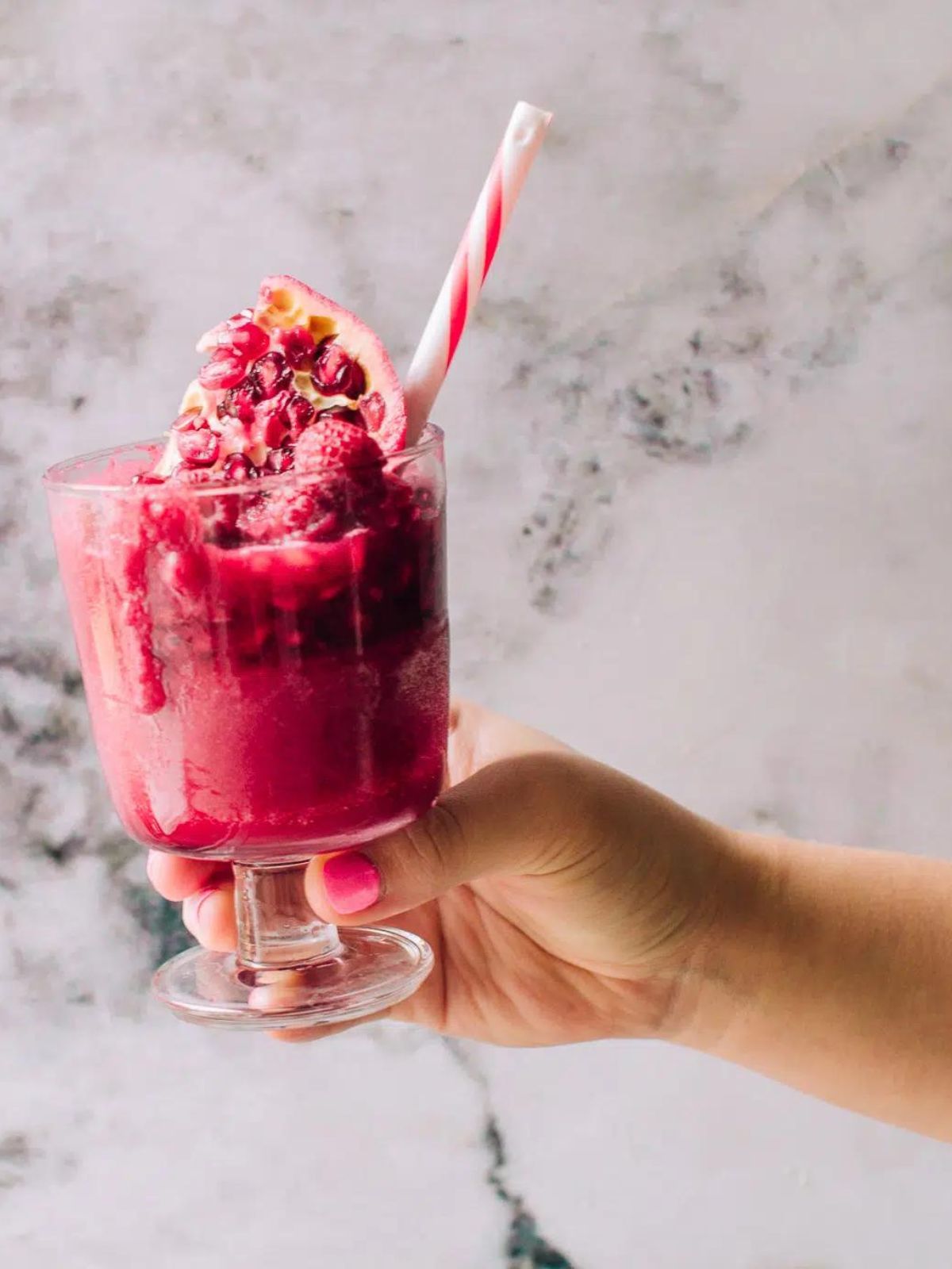 beet smoothie with pomegranate and a straw. 