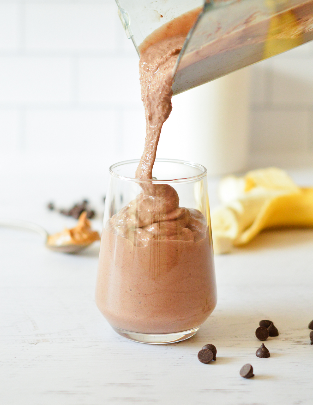 pouring a chocolate smoothie into a glass. 