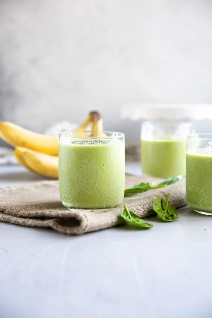 green smoothies in front of bananas. 