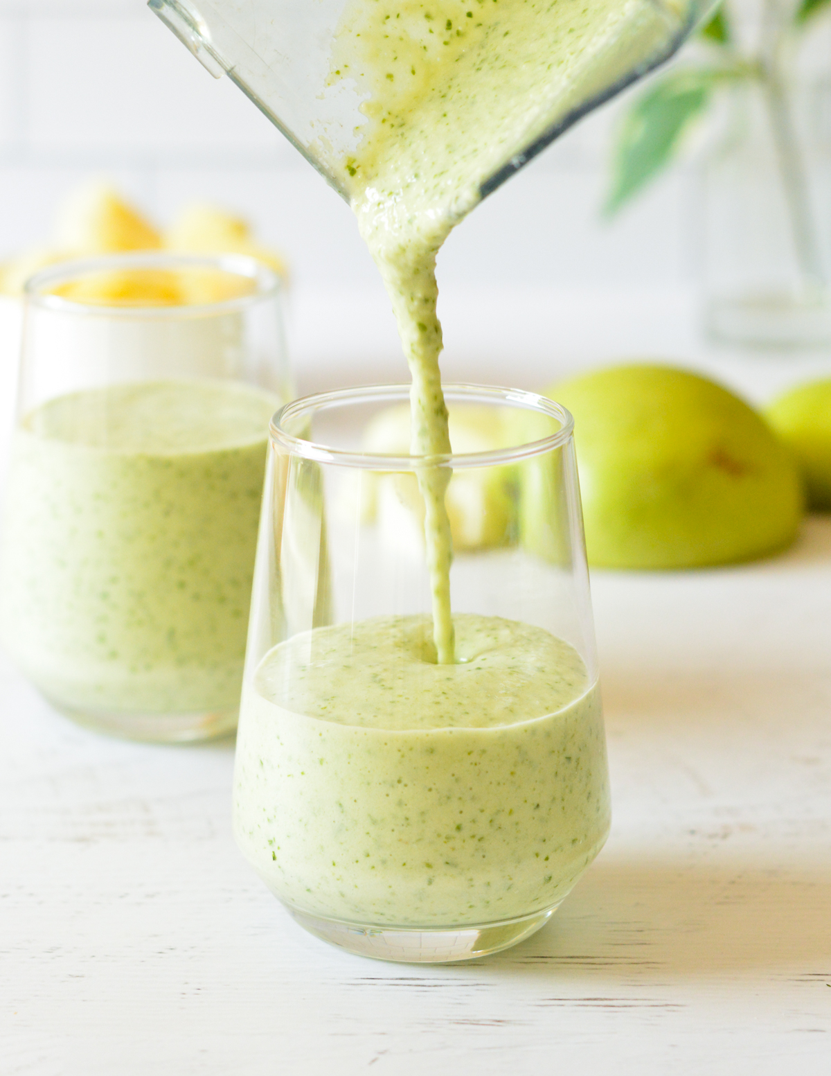 pouring a green smoothie into a glass.