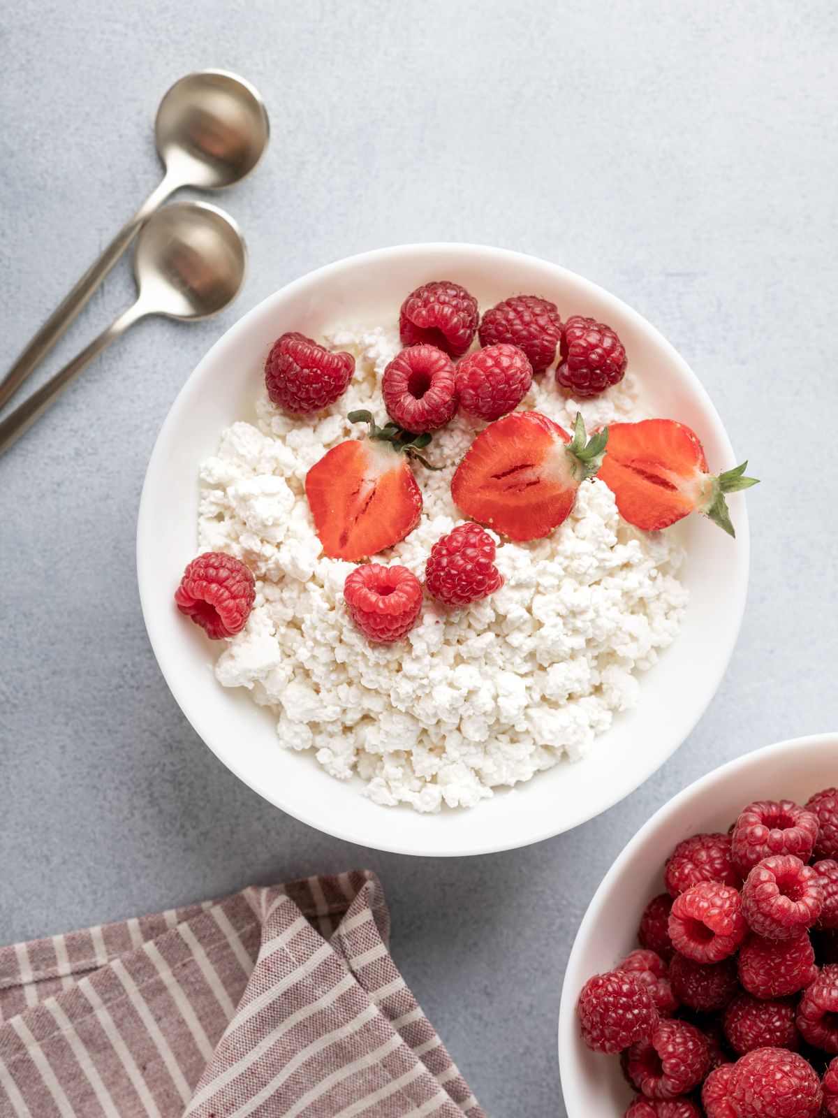 a bowl of cottage cheese with raspberries and strawberries.