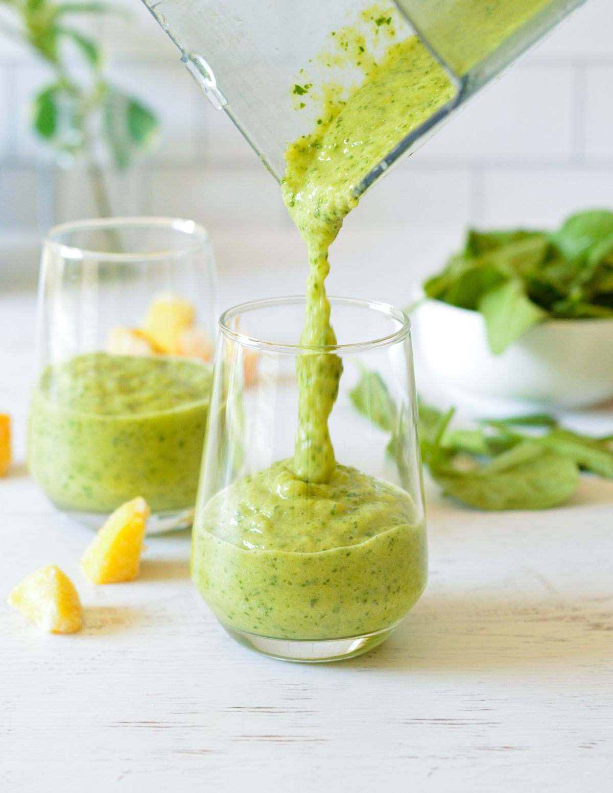 pouring a green smoothie into a glass.