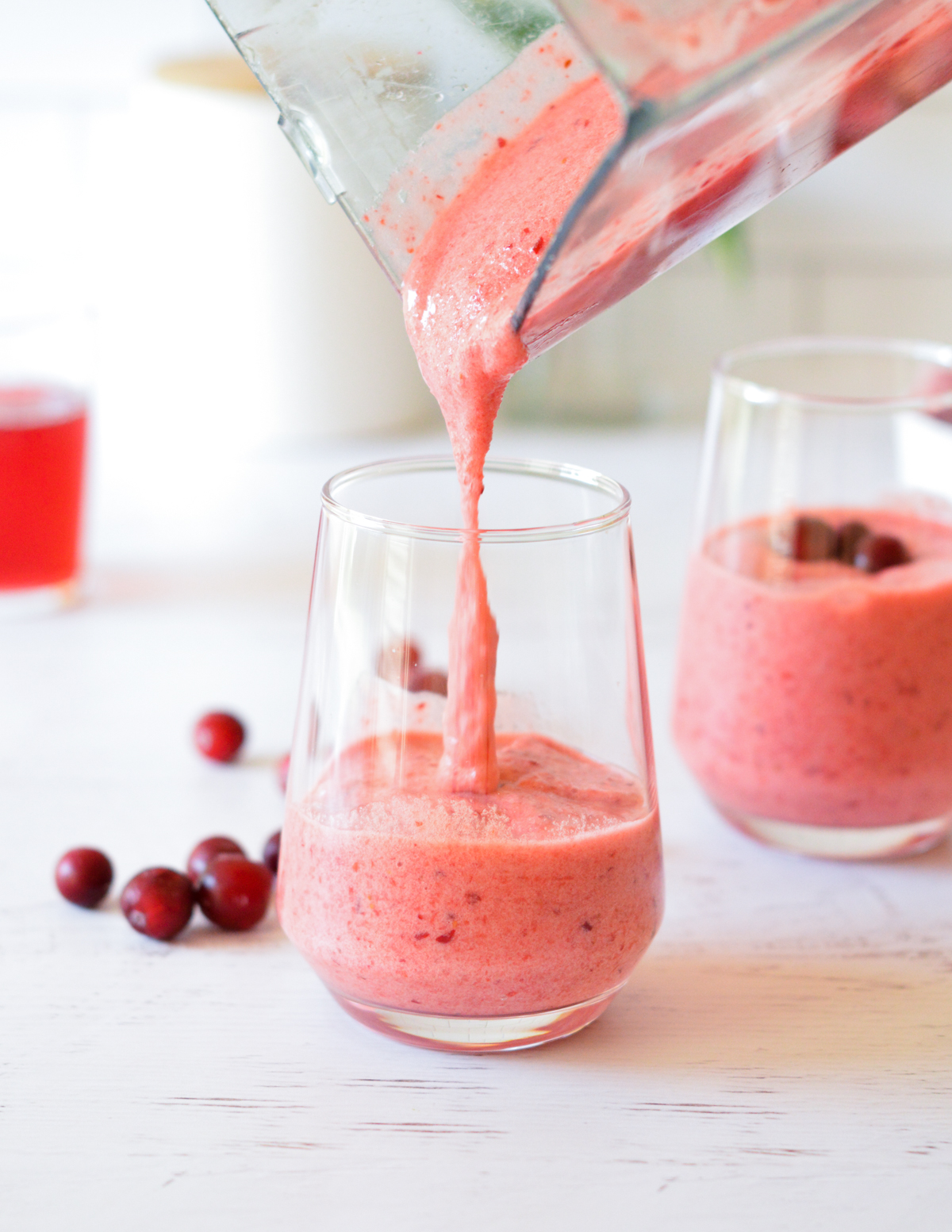 pouring cranberry smoothie into a glass.