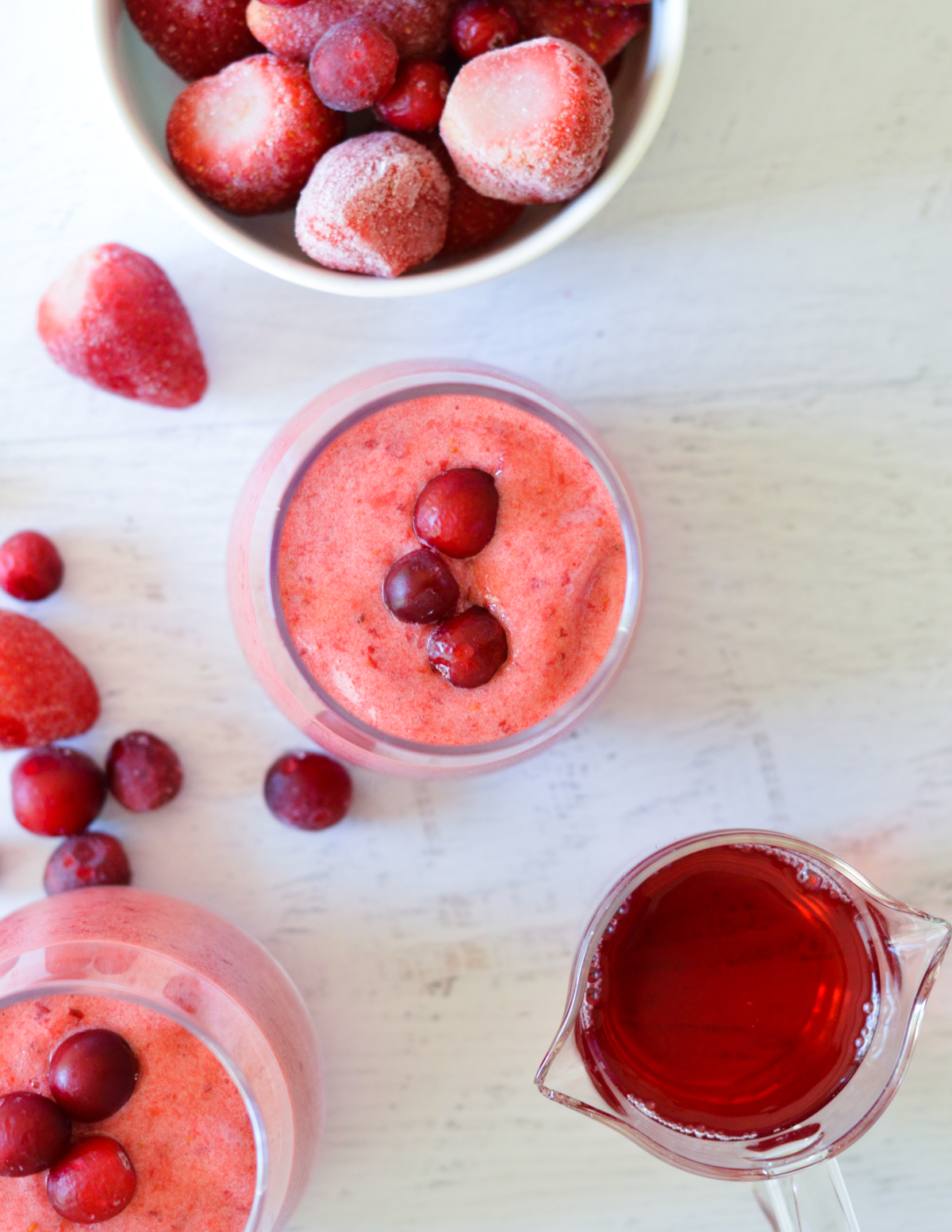 the top of a cranberry smoothie near strawberries and juice.