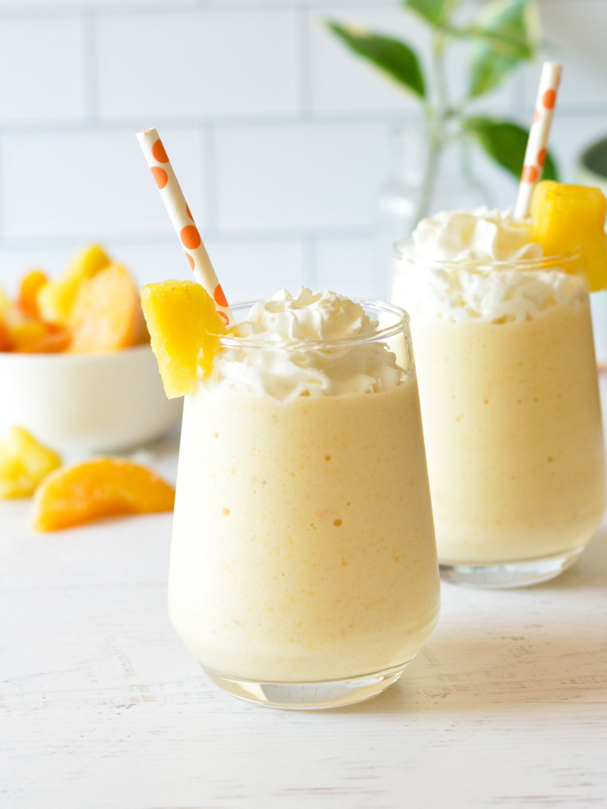 peach pineapple smoothies with whipped cream and pineapple.