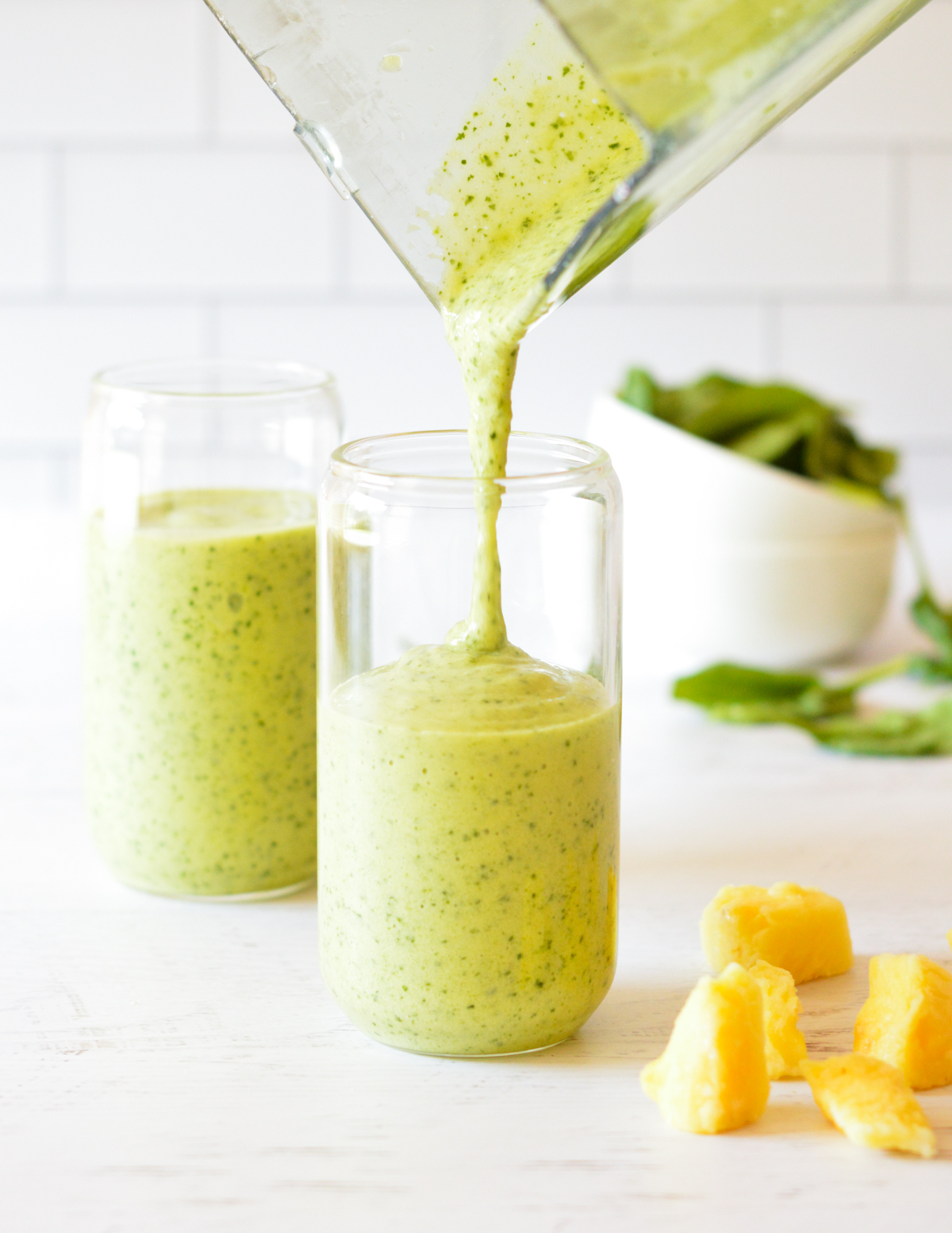 pouring a green smoothie into a glass.