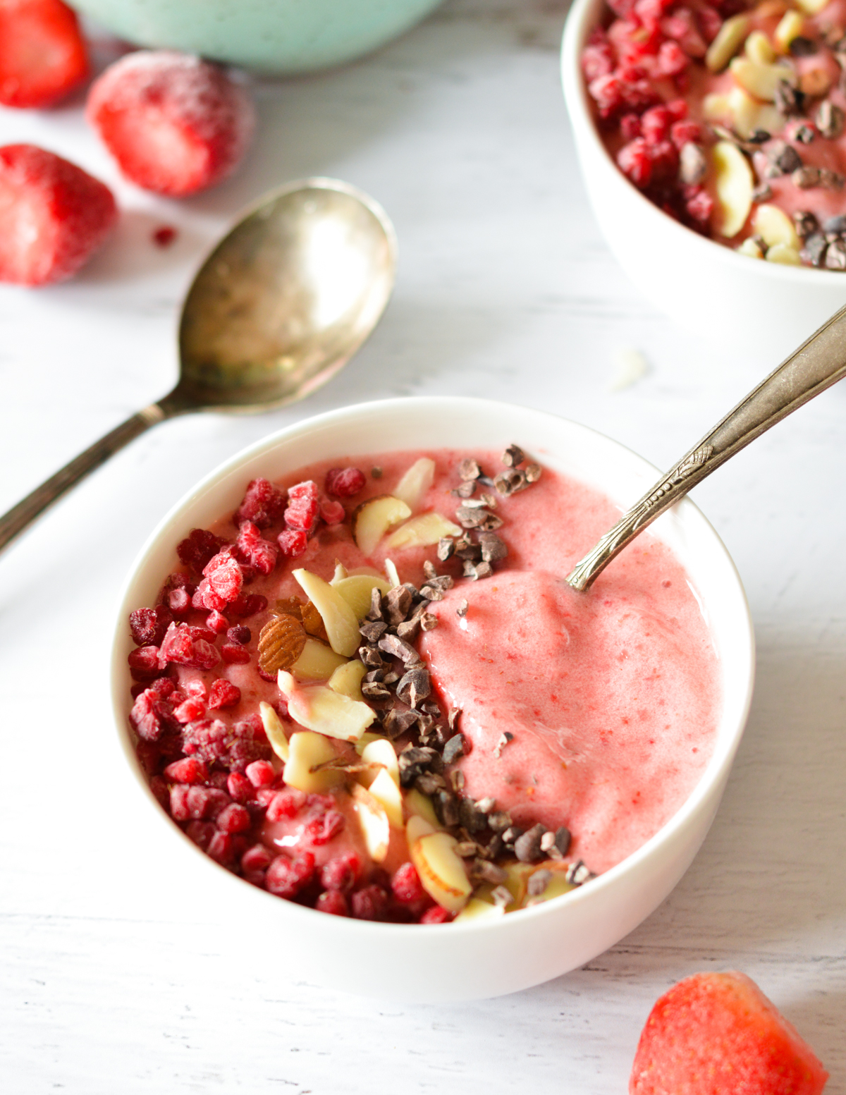 strawberry smoothie bowl with cacao nibs, almonds and raspberries on top.