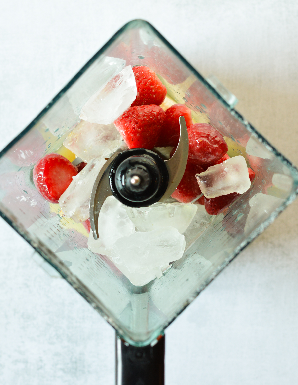 blender with strawberries, banana, and ice inside.