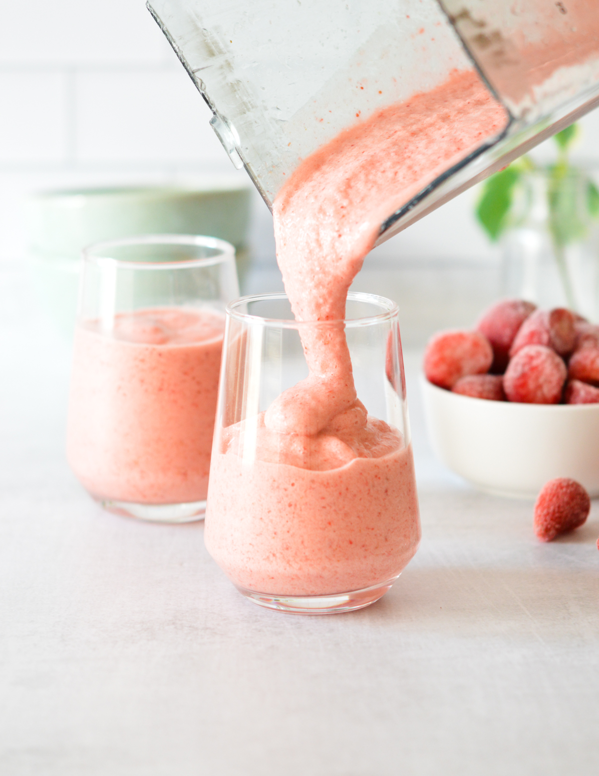 pouring a strawberry smoothie into a glass.