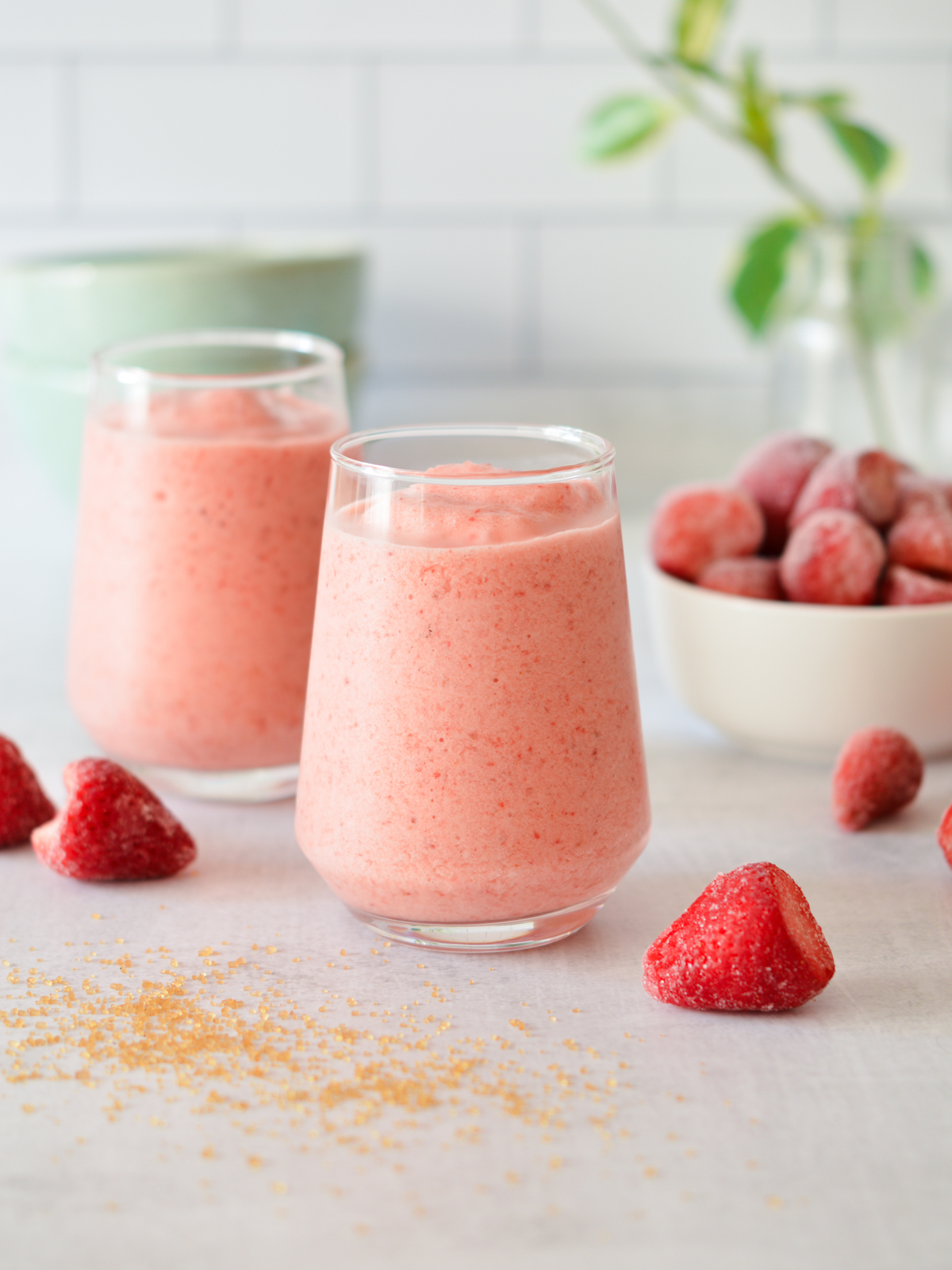 strawberry smoothies next to a bowl of strawberries.