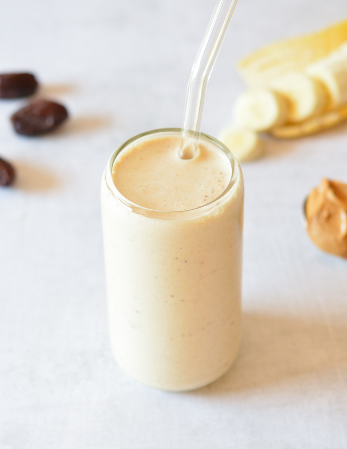 top of a peanut butter smoothie with a glass straw.