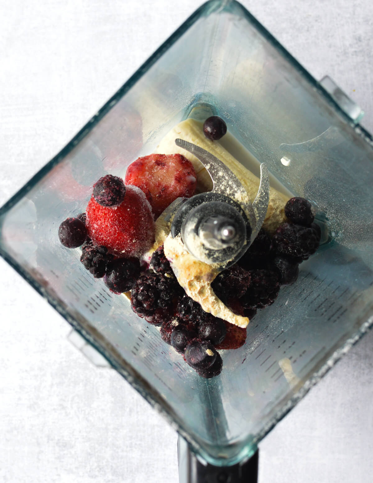 mixed berries, banana, protein powder, and yogurt in a blender.